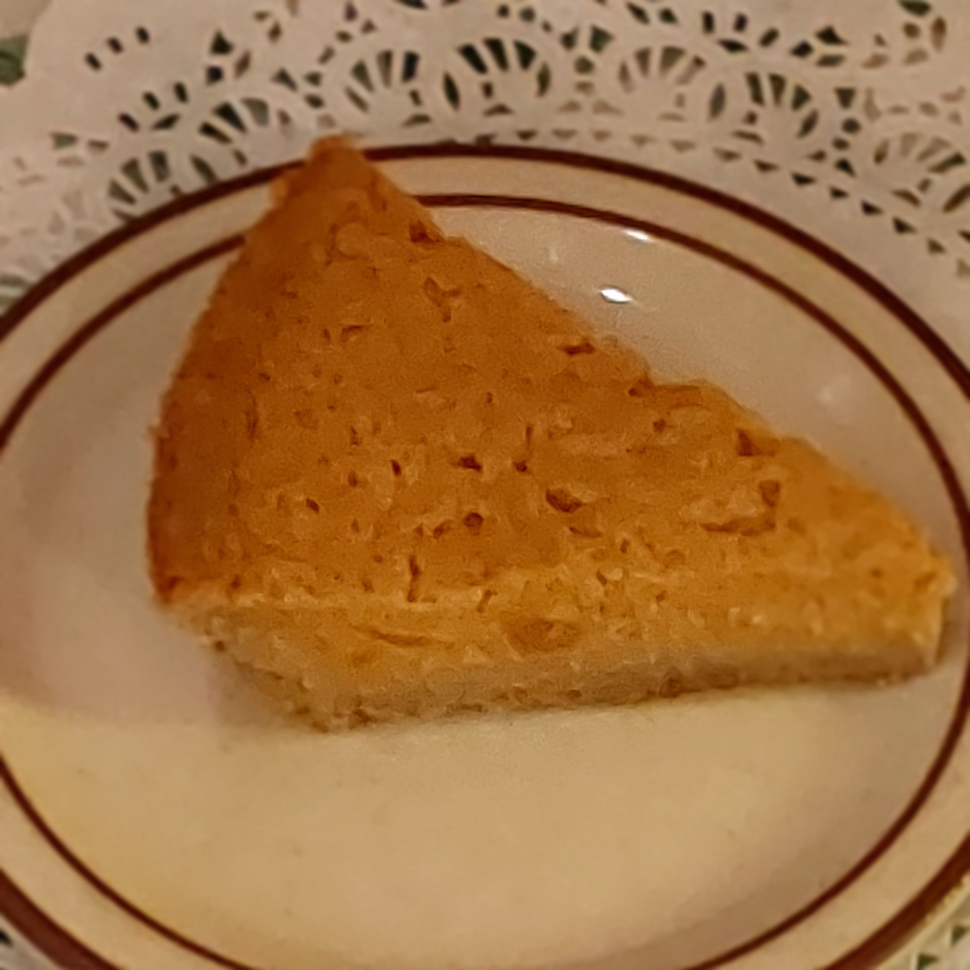 Slice of golden-brown cake on a white plate with brown rim stripes