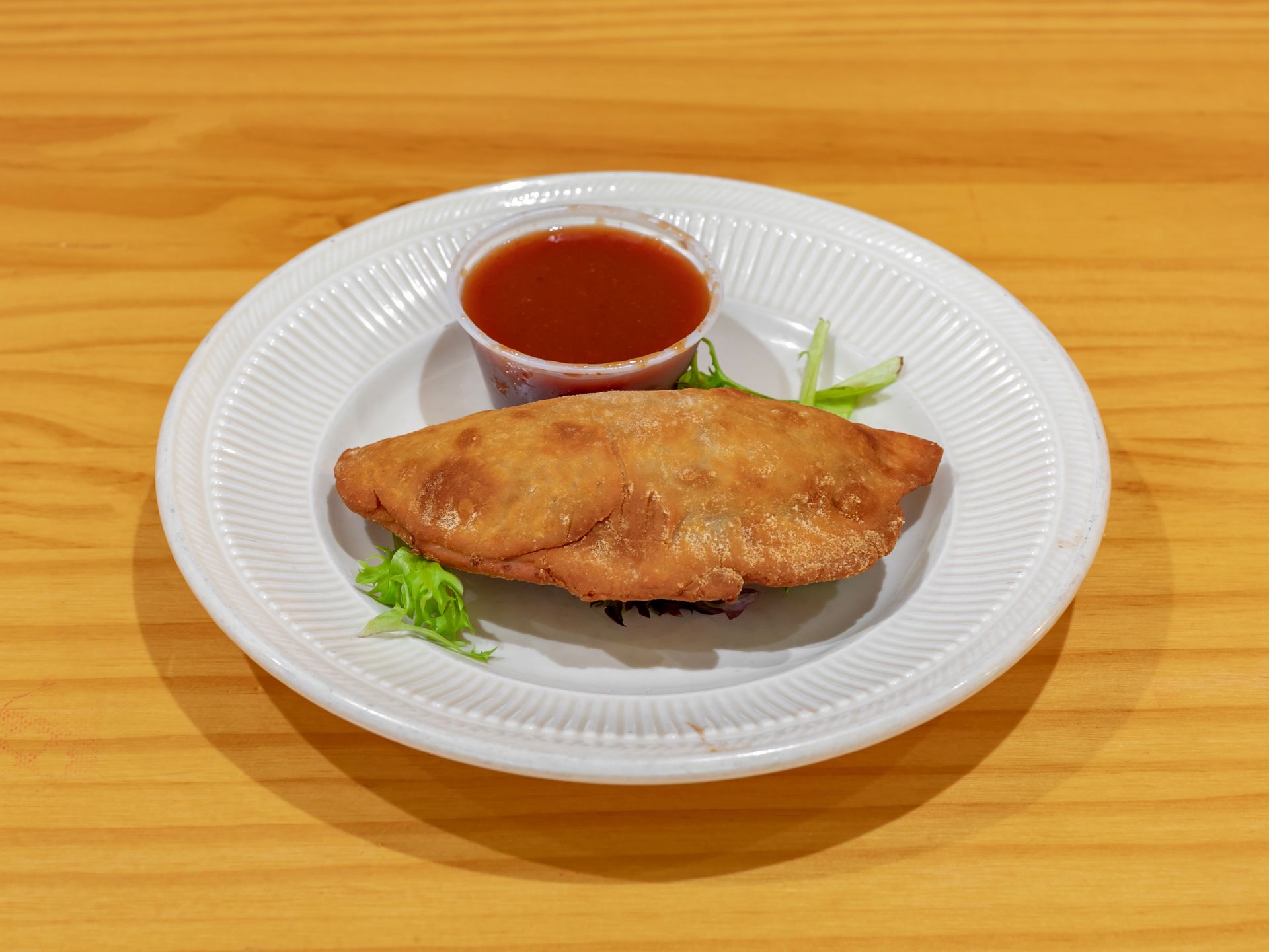 Fried pastry with dipping sauce on a white plate