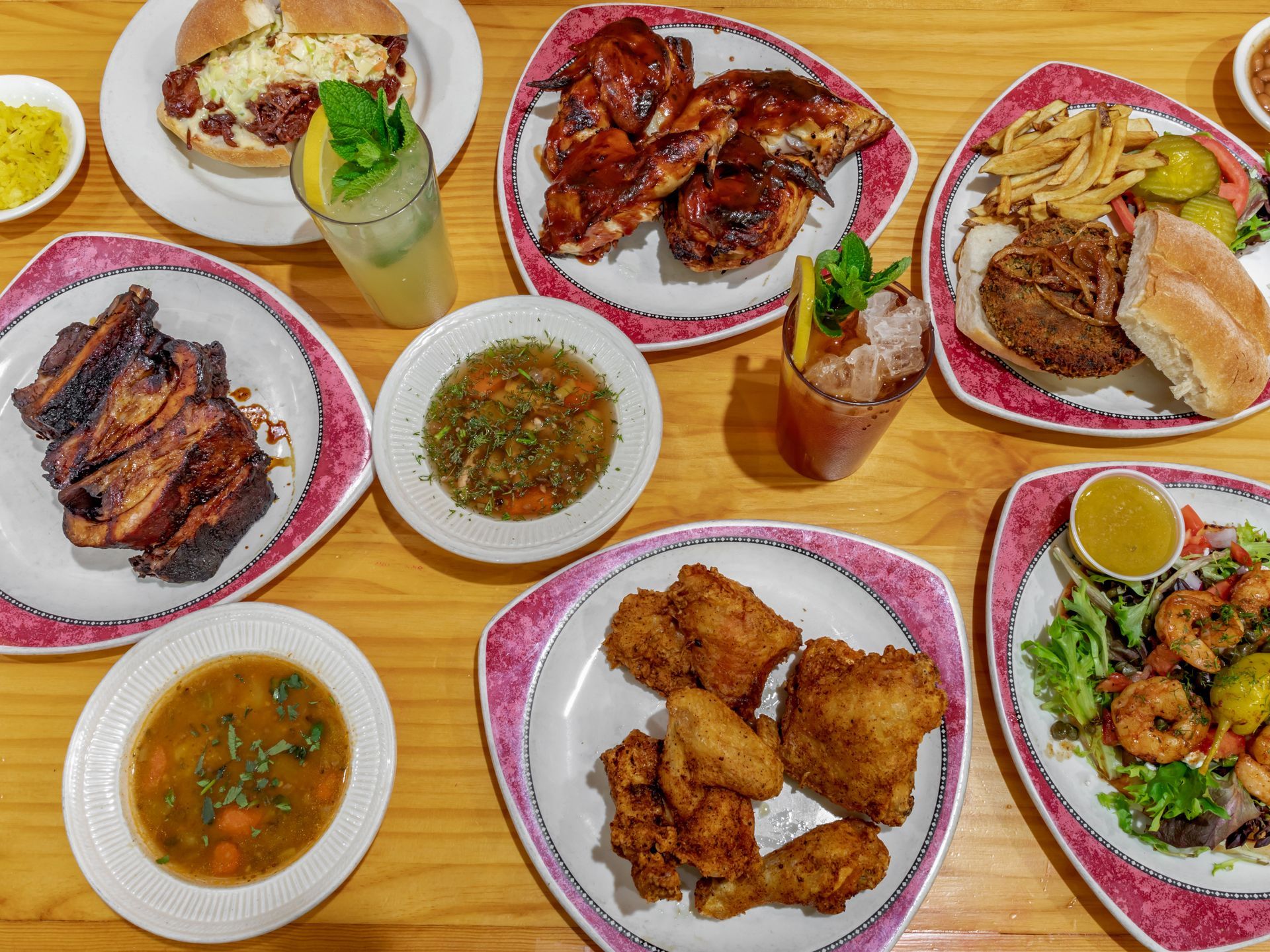 Assorted fried dishes, soups, and rice plates arranged on a table with drinks and condiments.