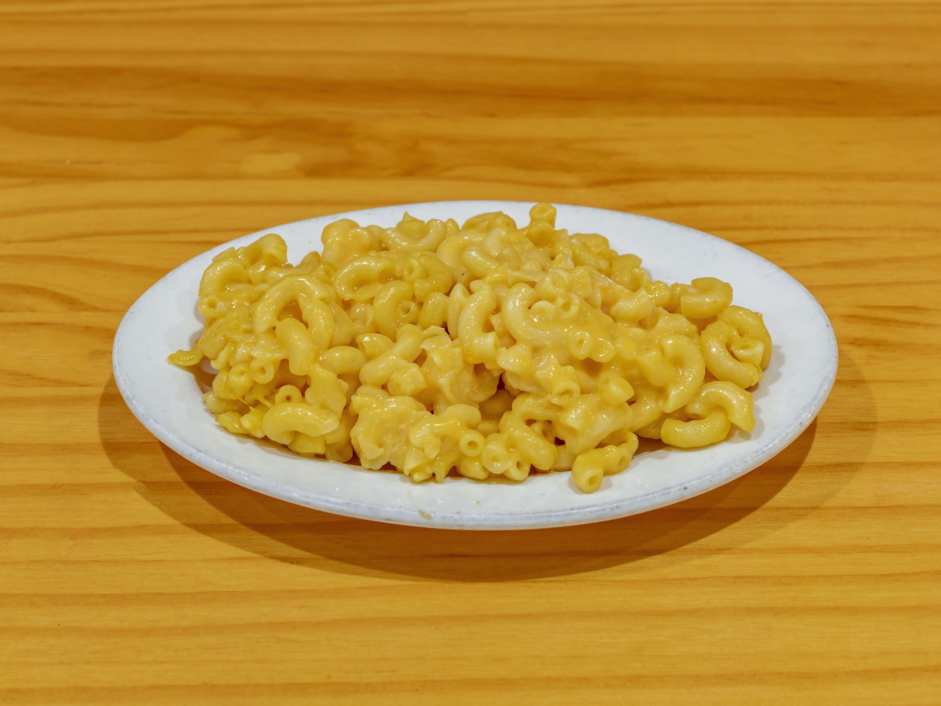 Plate of macaroni and cheese on a white dish against a wooden table background