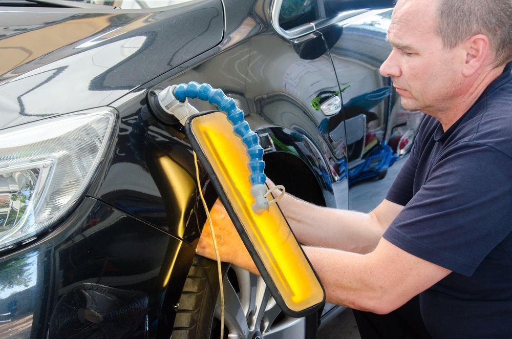 Man Using a Dent Repair Tool on a Black Car — Bowen Automotive in Bowen, QLD