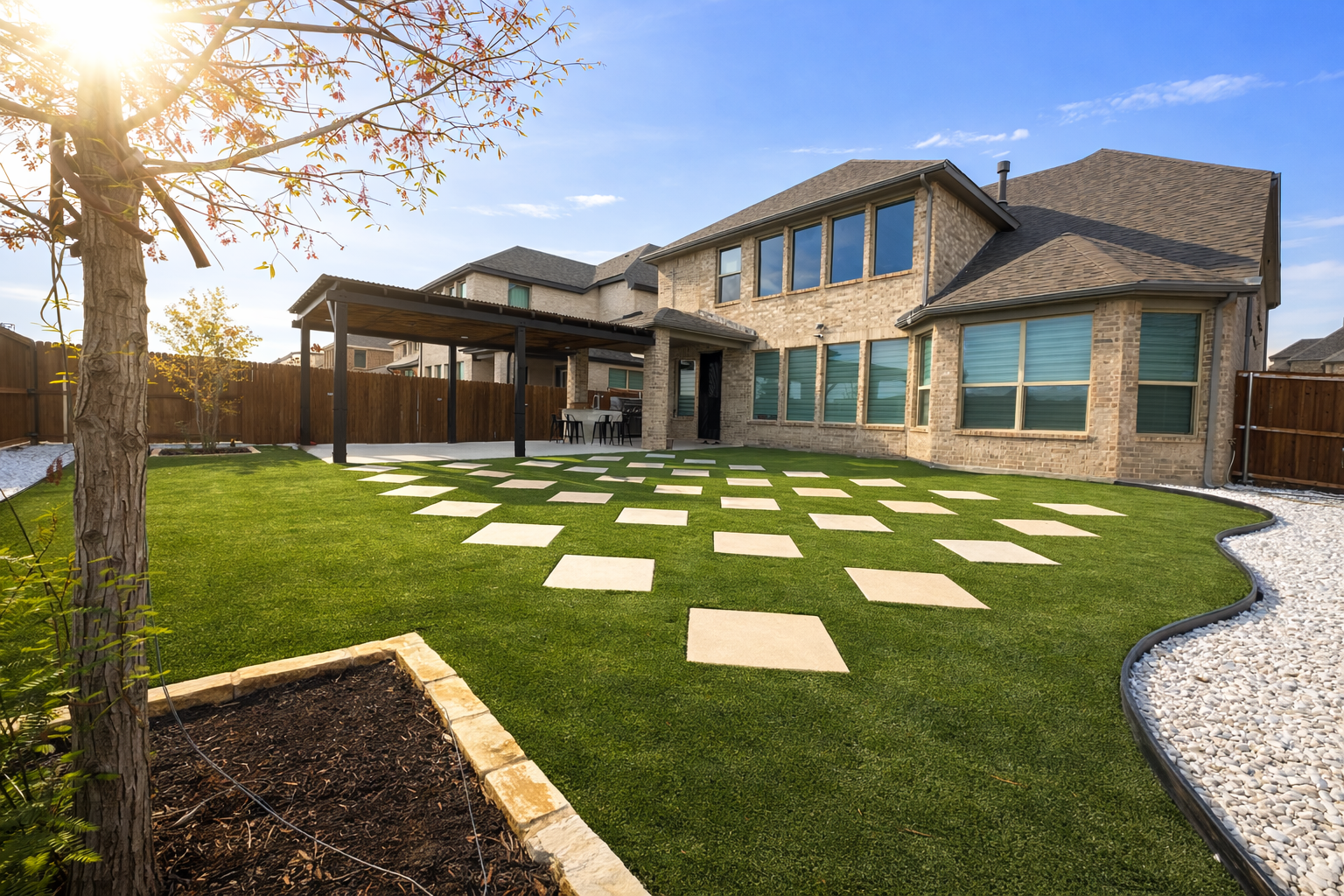 Green lawn with white square stepping stones, brown fence, and clear sky.