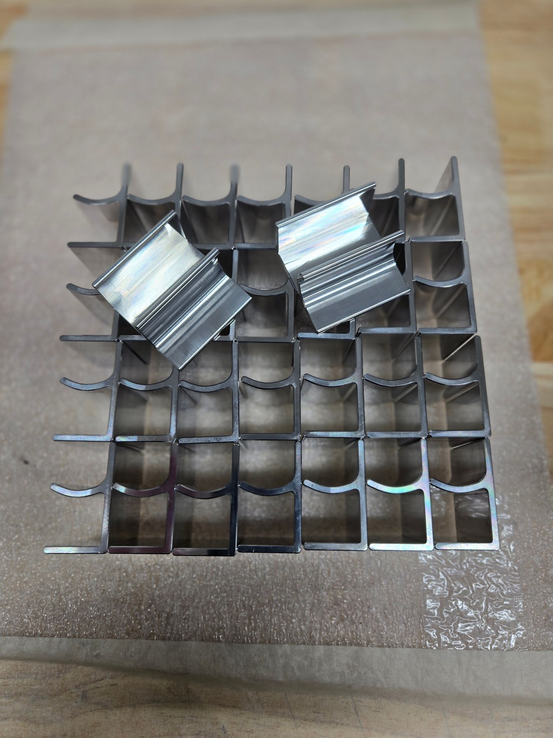 Metal grid with two shiny clips on a brown surface.