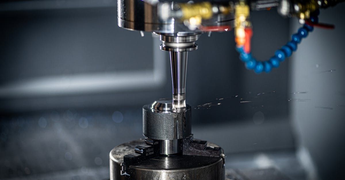 CNC machine milling a metal part. Close-up shows a spinning tool cutting with water spray.
