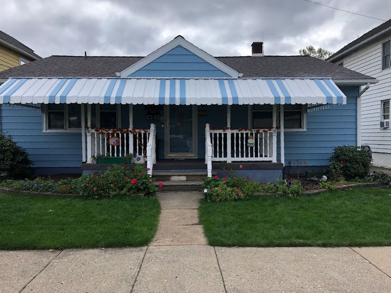 A blue house with a white awning on the front porch.