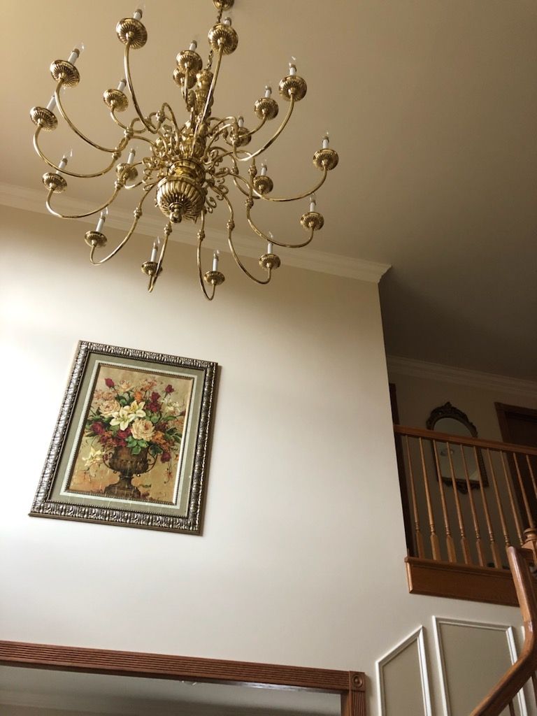 A picture of a vase of flowers hangs on a wall above a chandelier