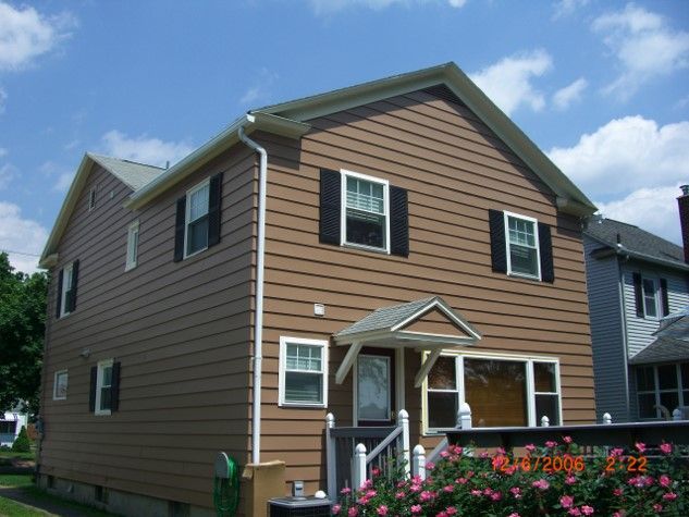 A brown house with black shutters on the windows
