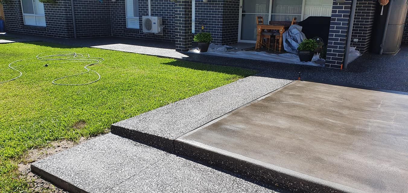 A concrete walkway leading to a lawn in front of a house. — MidCoast Concreting in Mount George, NSW