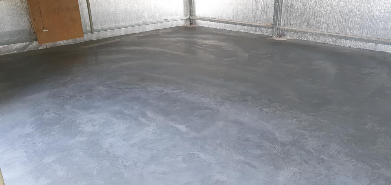 A concrete floor in a garage with a door in the background. — MidCoast Concreting in Nabiac, NSW