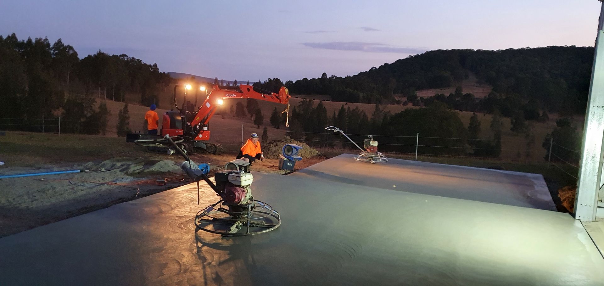 A group of construction workers are working on a concrete floor at night. — MidCoast Concreting in Mount George, NSW