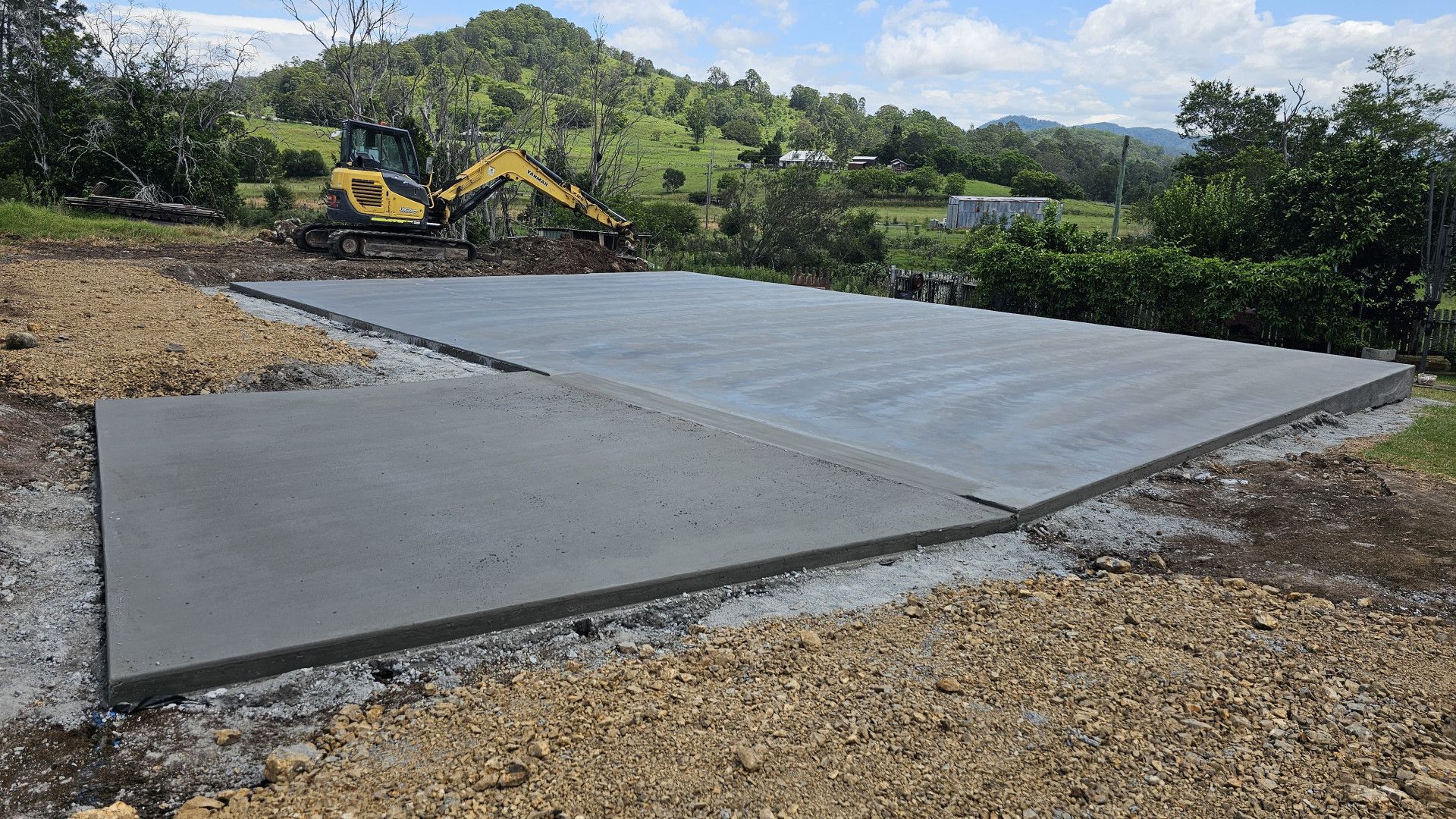 A large concrete slab is being built with a bulldozer in the background.— MidCoast Concreting in Hallidays Point, NSW