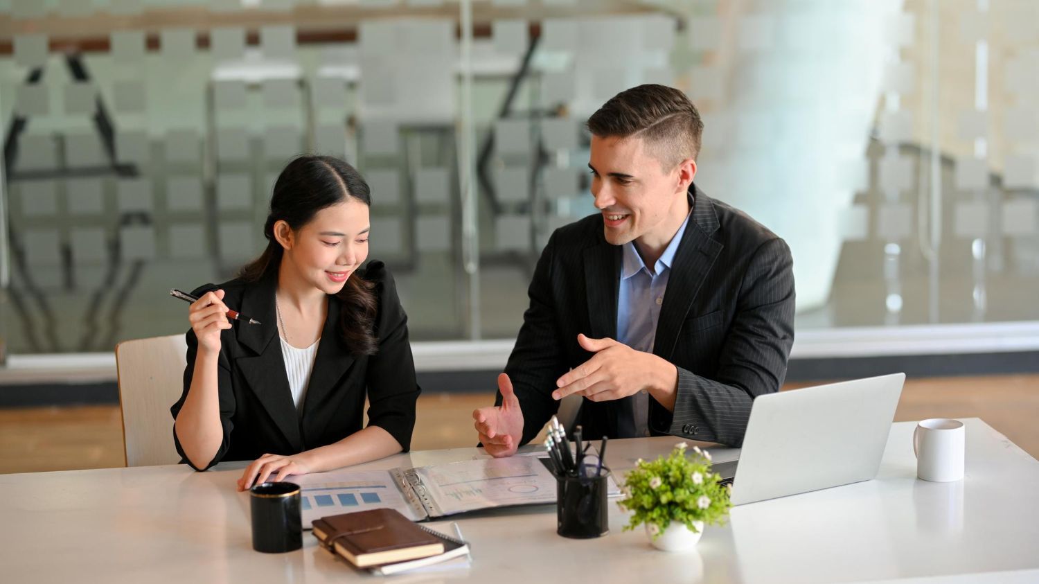 Business team reviewing financial chart, pointing to data on a paper.