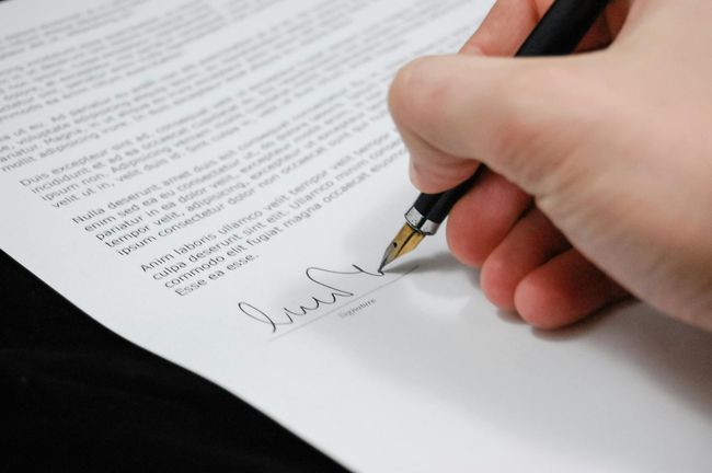 Hand signing a document with a fountain pen.