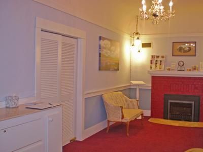 Cozy living room with red carpet, fireplace, chandelier, and a wicker chair by a window