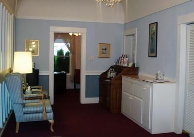 Cozy living room with blue chairs, white cabinet, red carpet, and a doorway to another room