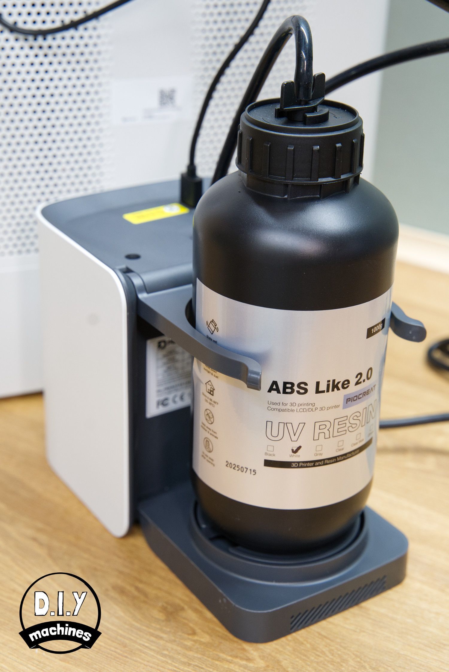 A bottle of Elegoo ABS-like 3.0 resin mounted in a dispensing pump station on a wooden desk.