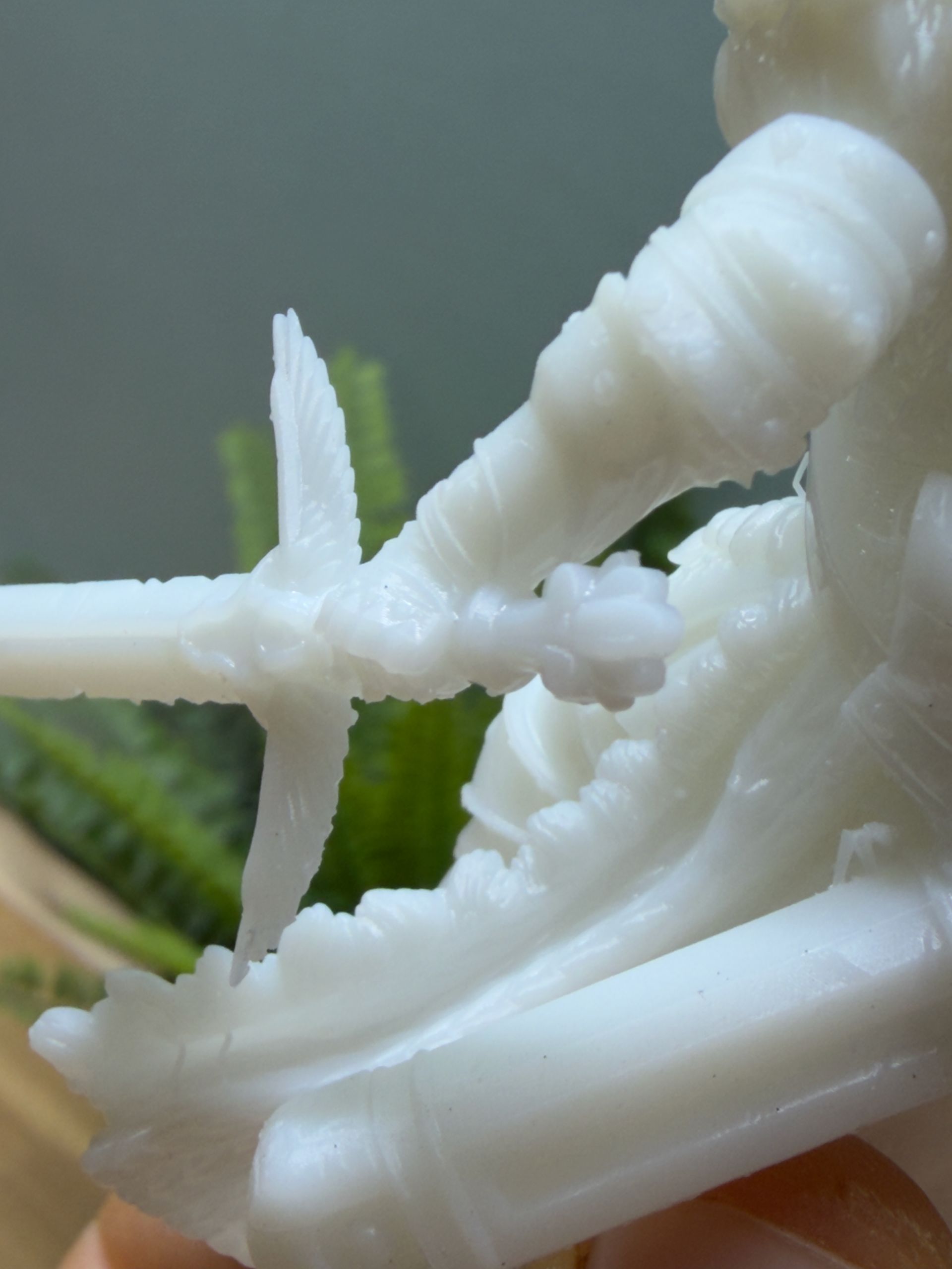 Close-up of a white 3D-printed figurine holding a sword, showing rough surface texture and print layer lines.