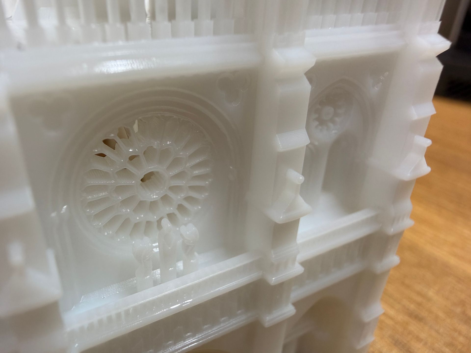A close-up of a white, 3D-printed architectural model featuring intricate rose window detail and gothic arches.