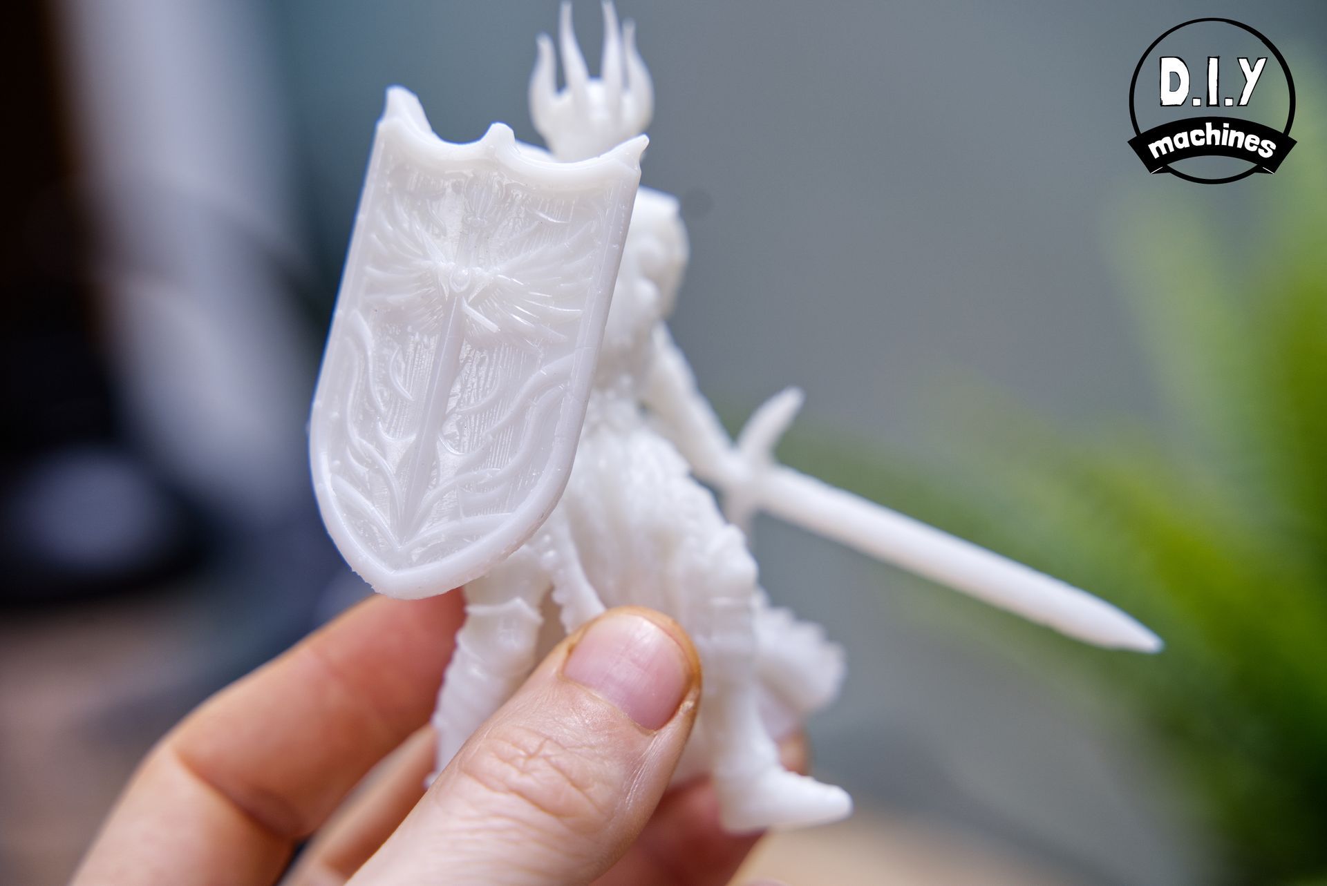 A person holding a small, white 3D-printed knight figurine with a shield and sword.