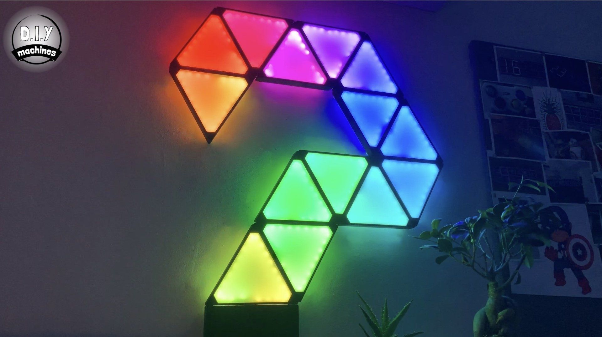 A geometric wall-mounted light installation forming a question mark shape, glowing in a vibrant rainbow gradient.