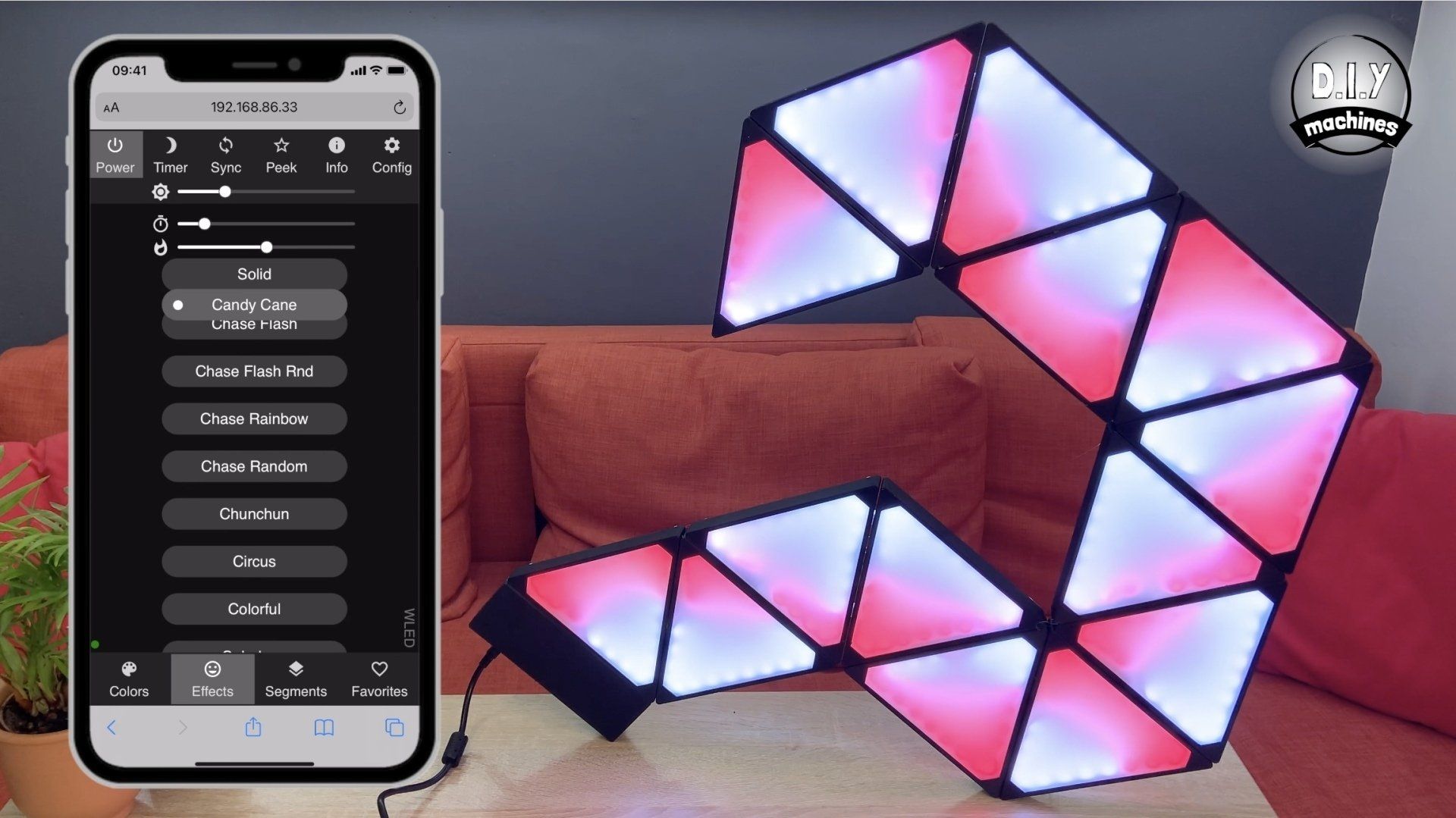 A smartphone app controls glowing, pink and white triangular LED light panels arranged on a table in front of a sofa.