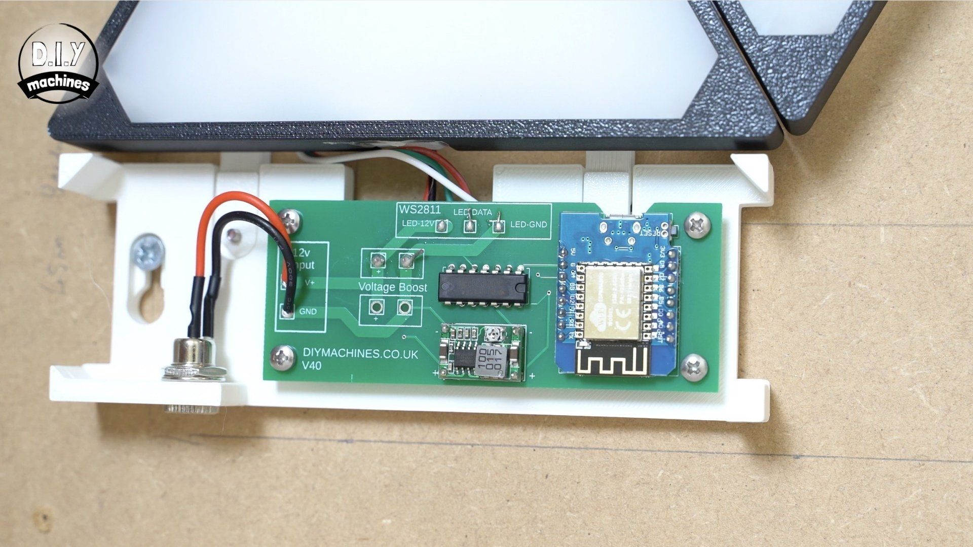 A green circuit board with a Wi-Fi module and power jack is mounted on a white 3D-printed bracket for a LED wall panel.
