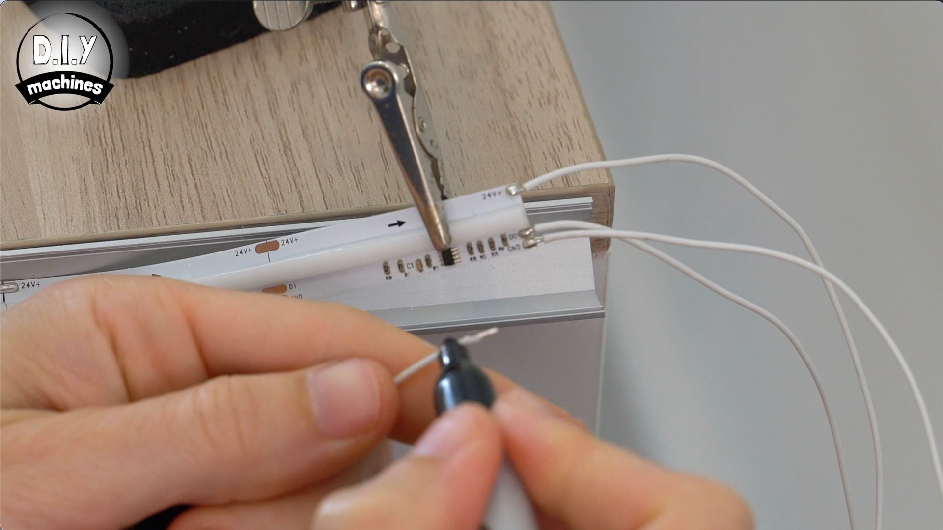 Close-up of hands using a marker to make a mark on a white cord, while another cord is secured by a clamp nearby.