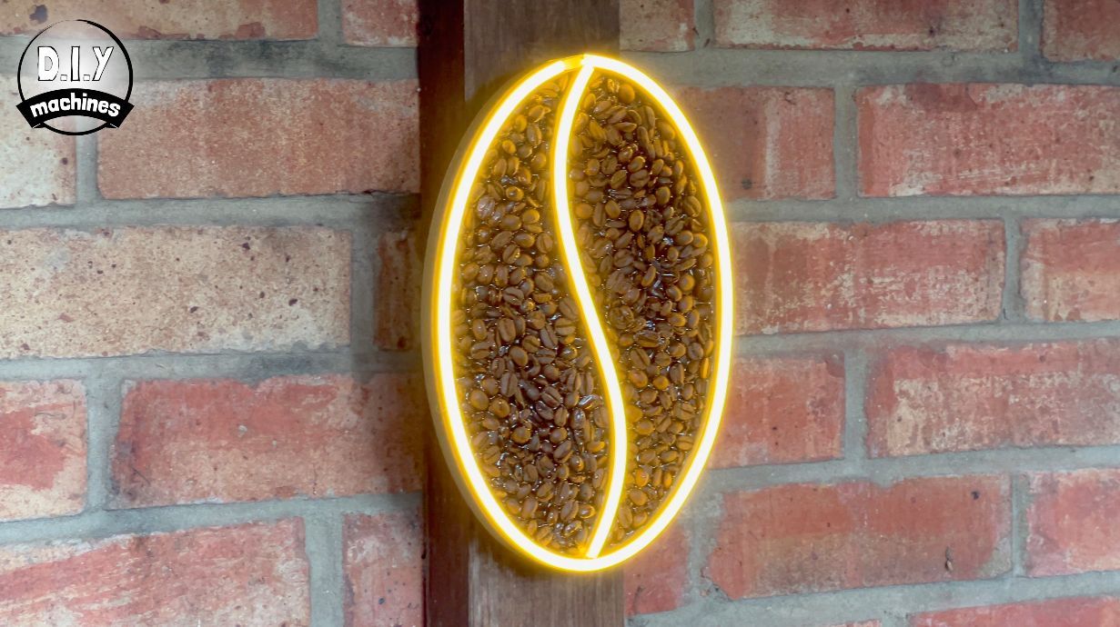 A coffee bean-shaped sign outlined in yellow neon, filled with roasted coffee beans, mounted on a rustic red brick wall.