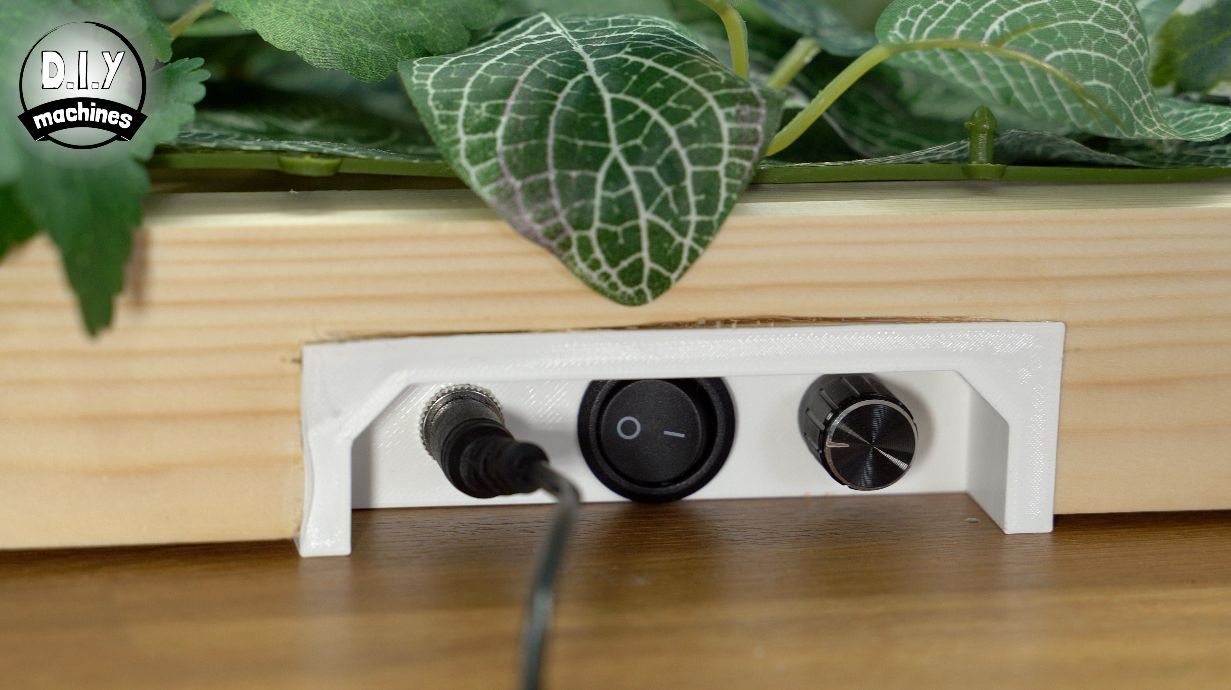 Close-up of a wooden-framed project with a recessed white control panel featuring a power jack, rocker switch, and dial.