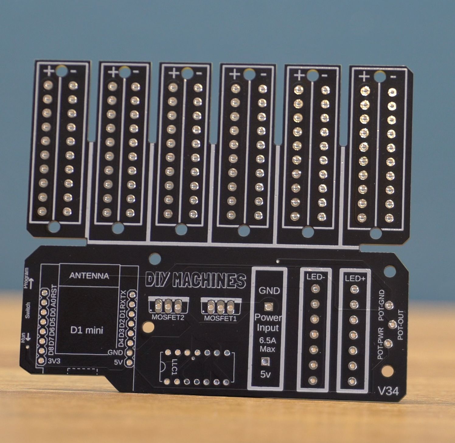A black printed circuit board (PCB) featuring six vertical columns for components and a base section with labeled ports.