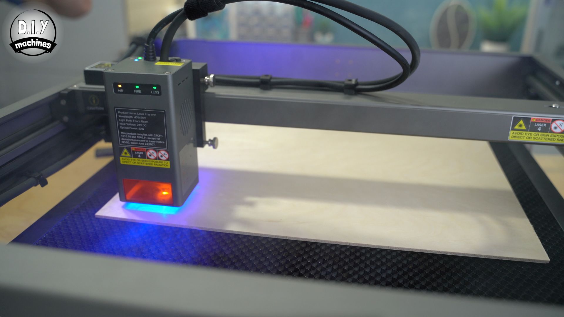 A laser engraver module with an active blue light beam positioned over a flat material on a honeycomb cutting bed.