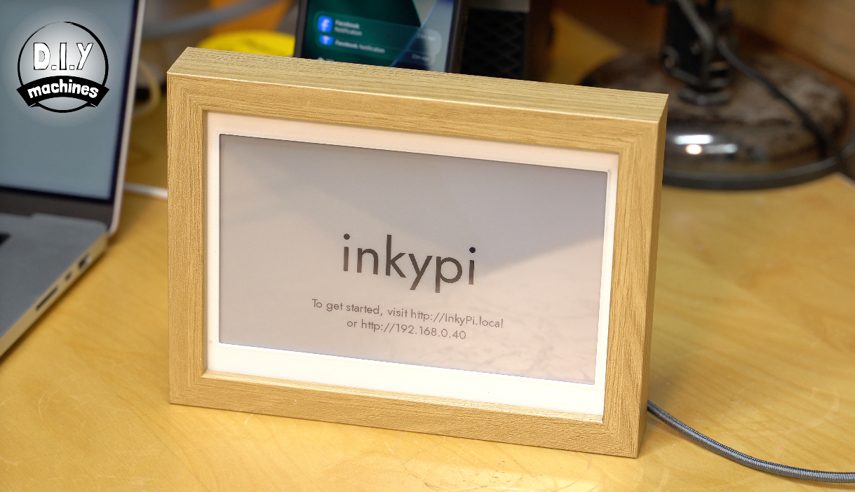 An electronic ink display in a light wood frame on a desk, showing the text