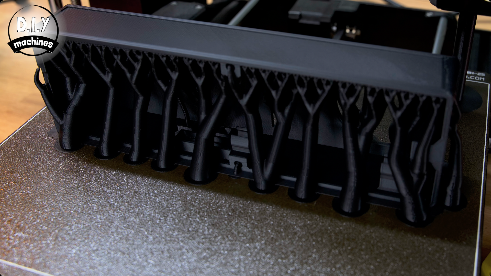 A black 3D print with dense, branching support structures rising from a textured build plate.
