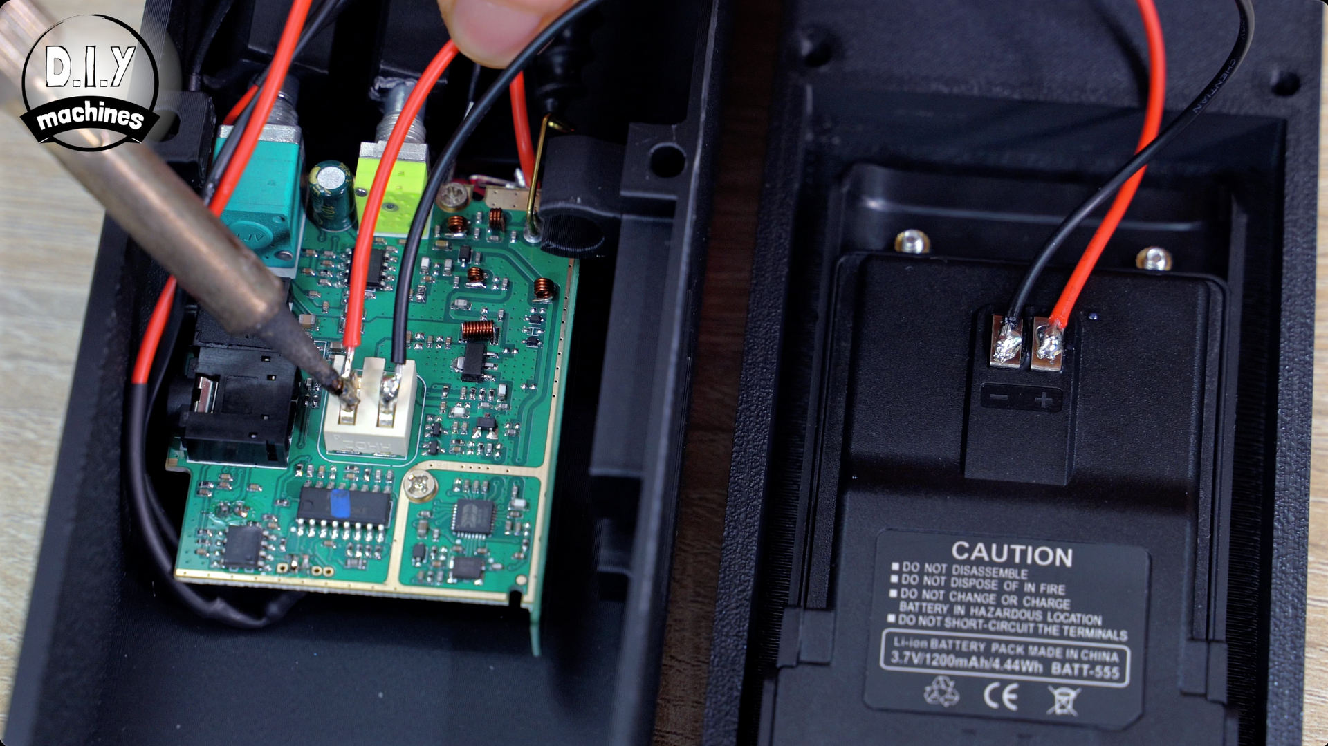 A soldering iron tip touching a circuit board wire connection inside an open black electronic casing.