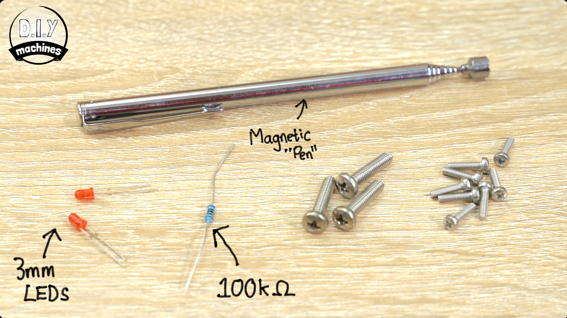 Components for an electronics project on a wood surface: a magnetic rod, two 3mm LEDs, a 100kΩ resistor, and several screws.