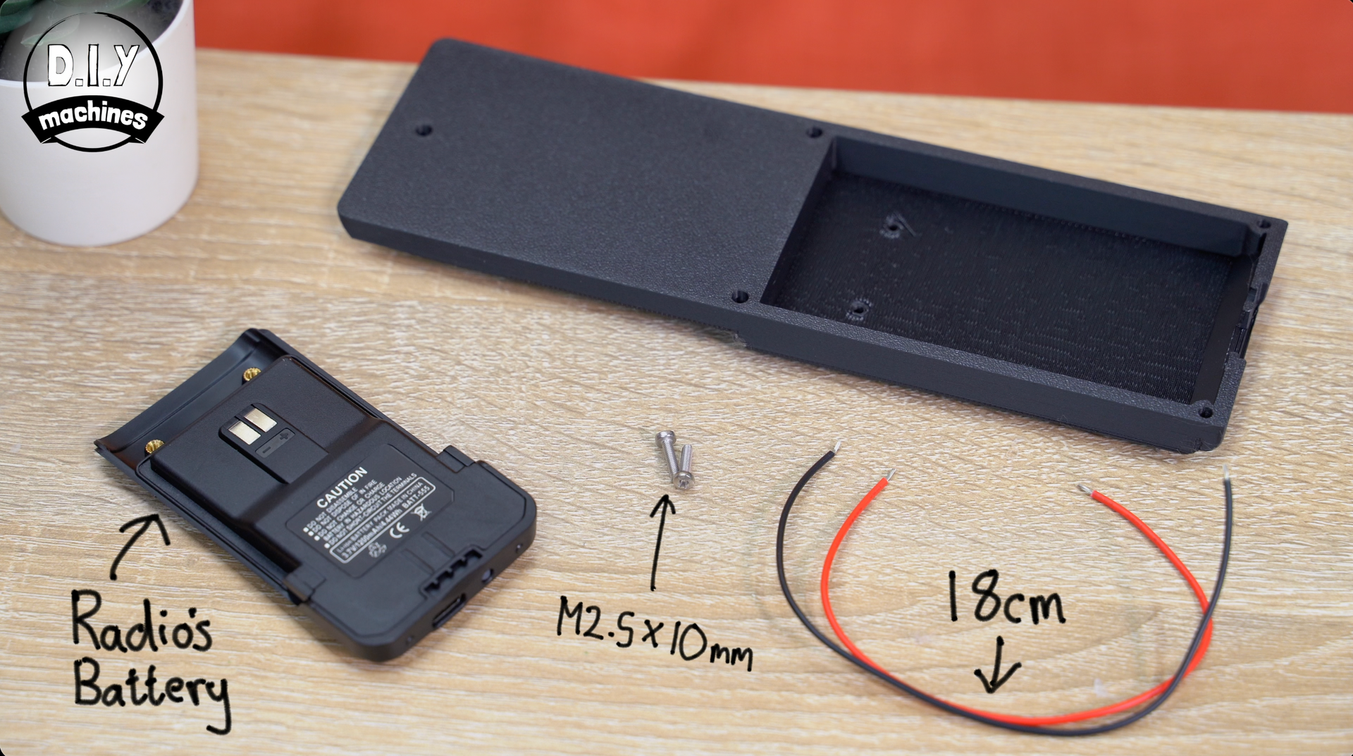 A radio battery, a small screw labeled M2.5x10mm, and two 18cm wires sit on a table next to a 3D-printed black battery case.