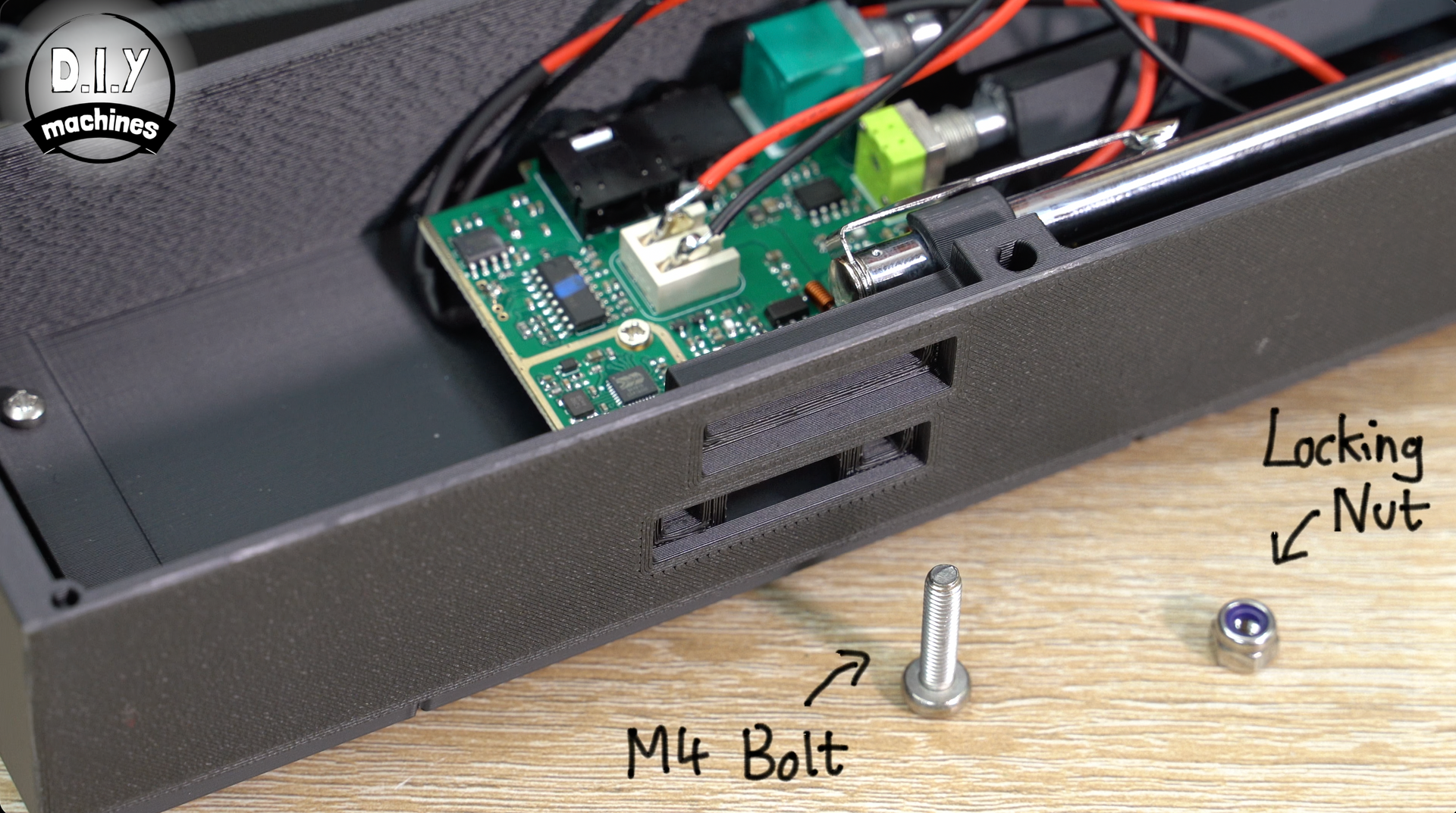 An M4 bolt and a locking nut sit next to a 3D-printed electronics housing on a wooden surface.