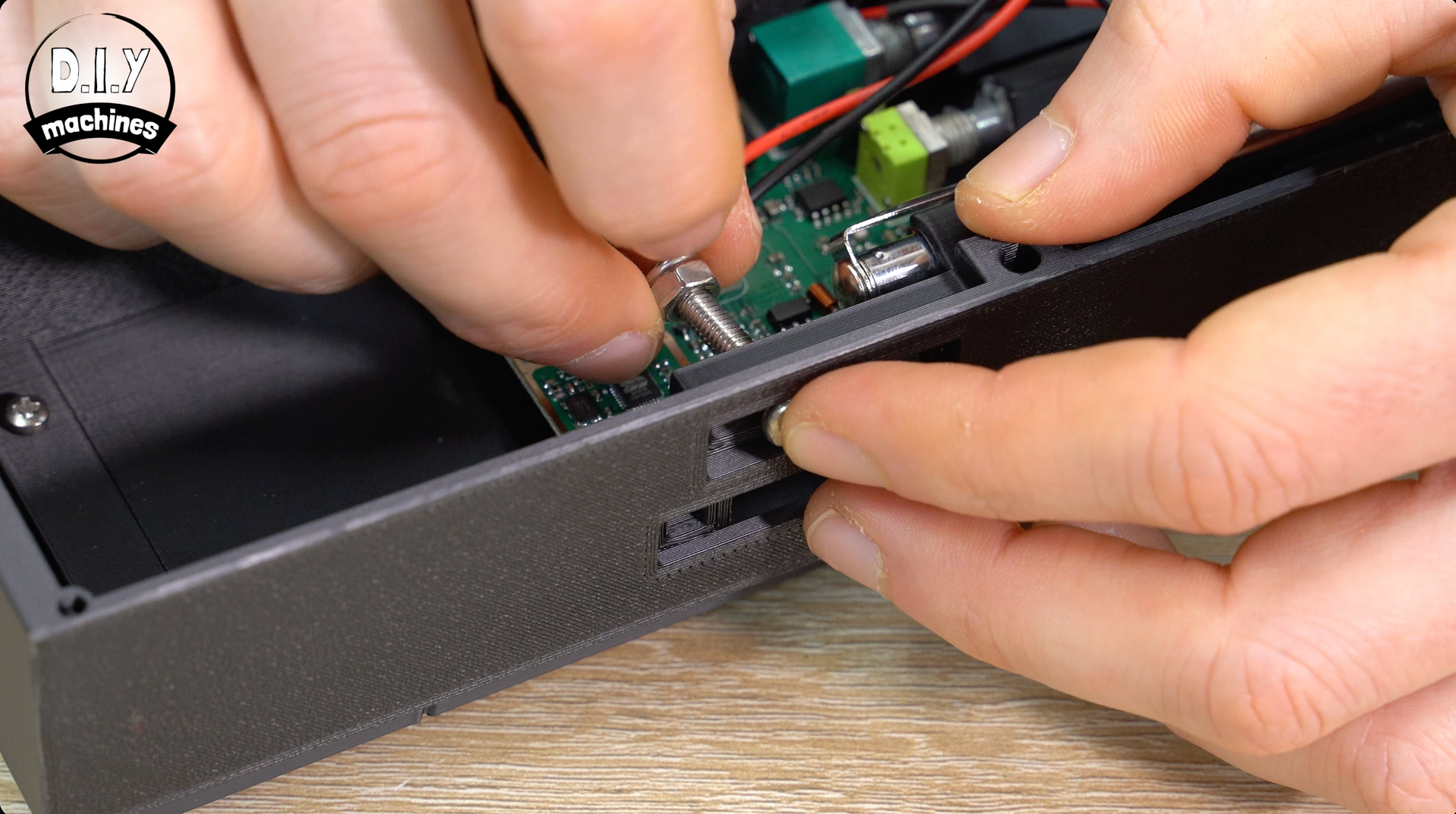 Hands aligning a metal potentiometer shaft through a hole in a 3D-printed electronics enclosure.