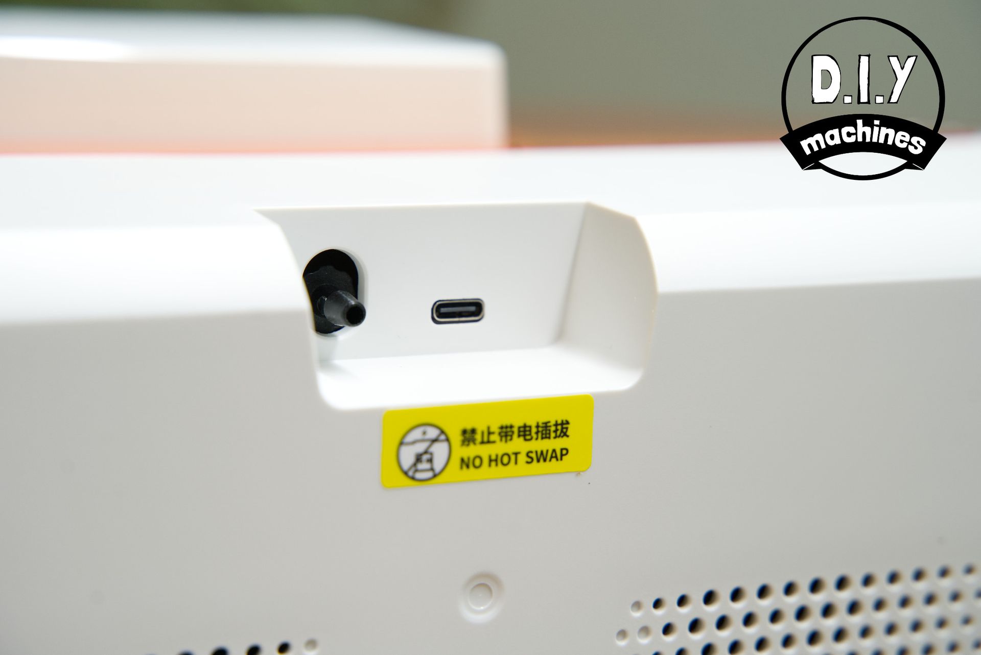 Close-up of a white device's rear panel featuring a black port, a USB-C port, and a yellow