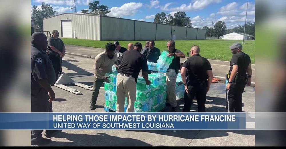 A group of people are standing around a pile of water bottles.