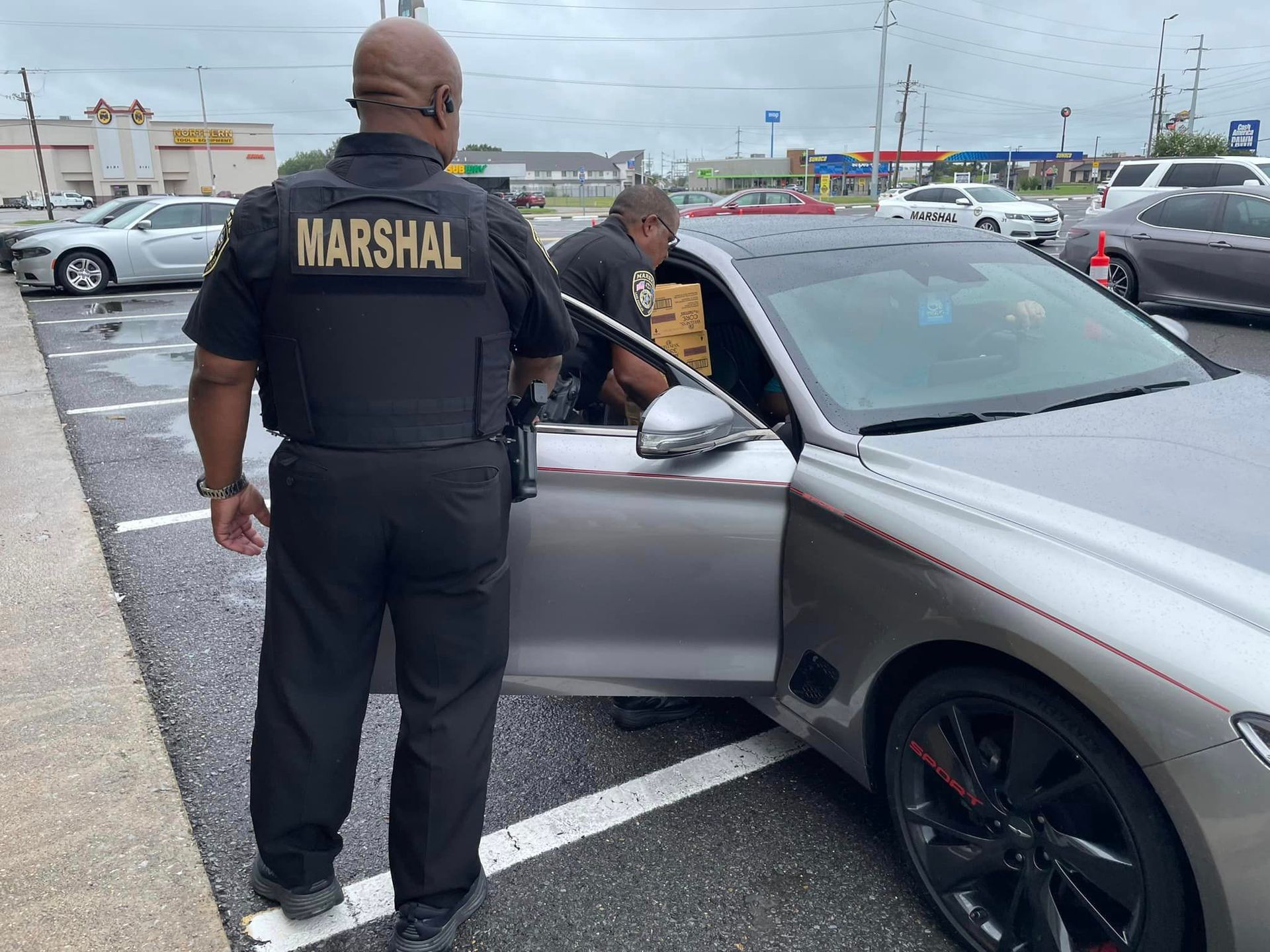 A man in a marshal uniform is standing next to a car