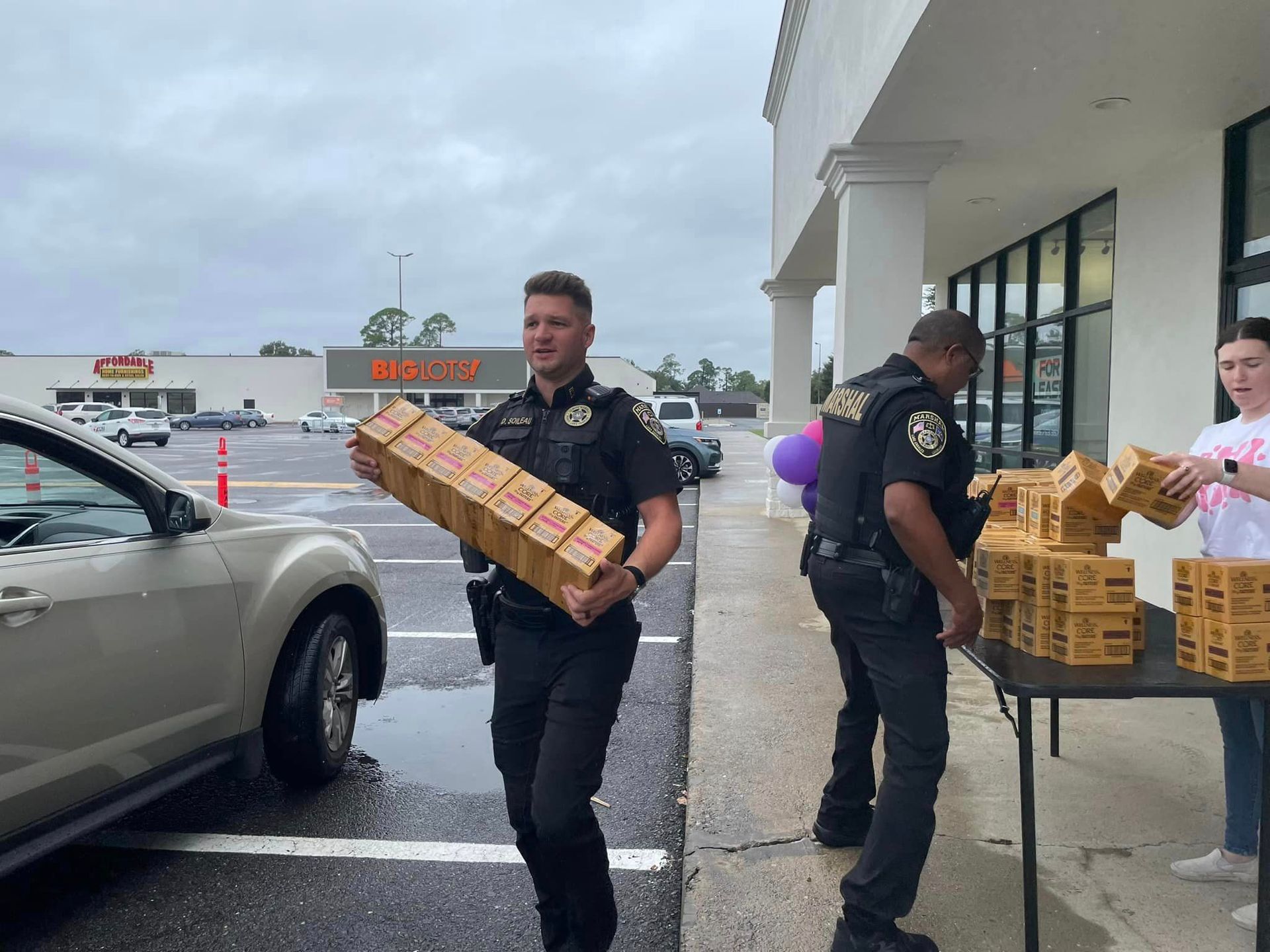 A group of Deputies are loading cat food in a parking lot.