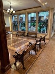 Elegant lobby with polished wood benches, large windows, and warm chandelier lighting