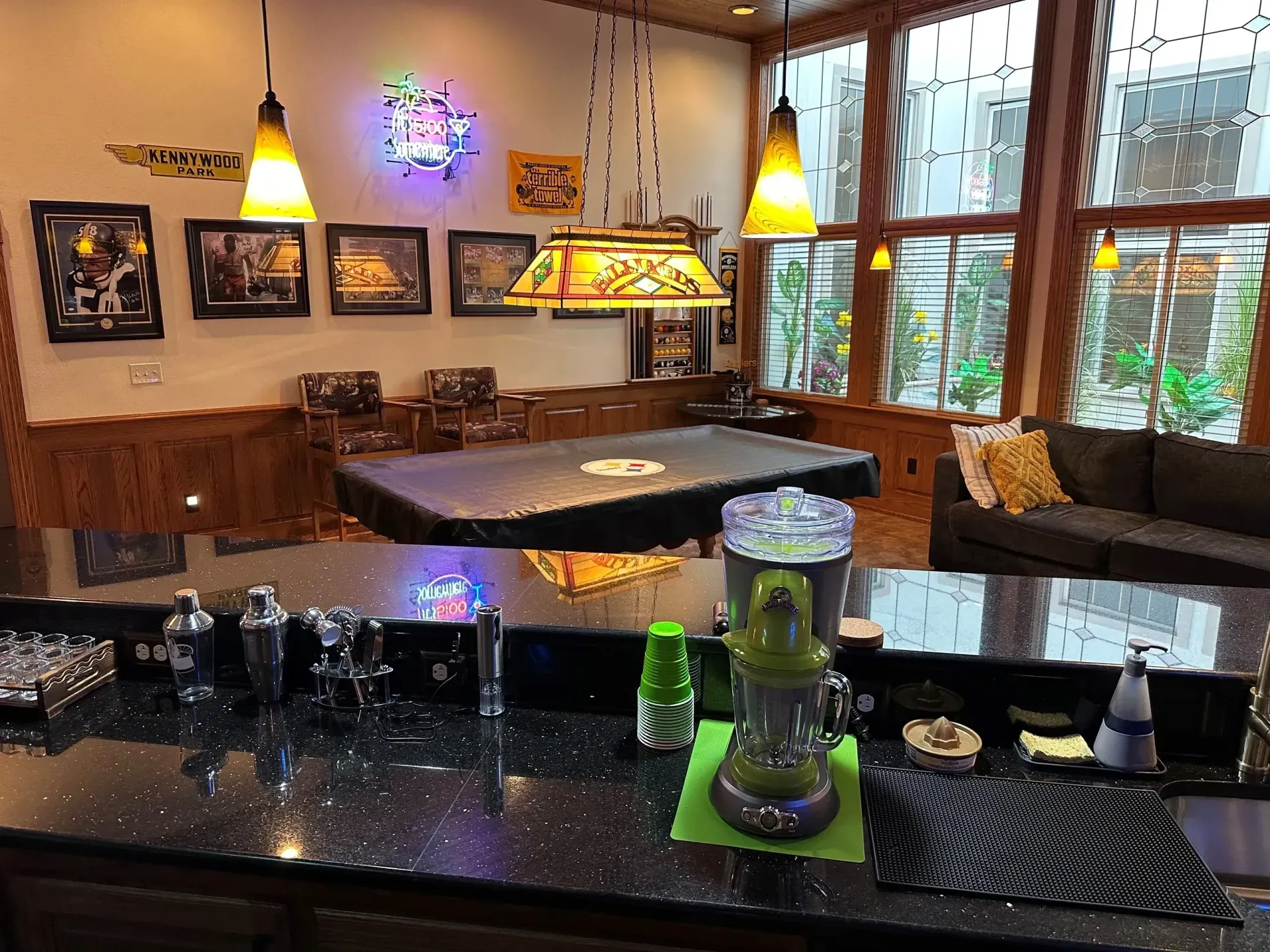 Cozy café dining area with black tables, colorful pendant lights, and large windows overlooking greenery