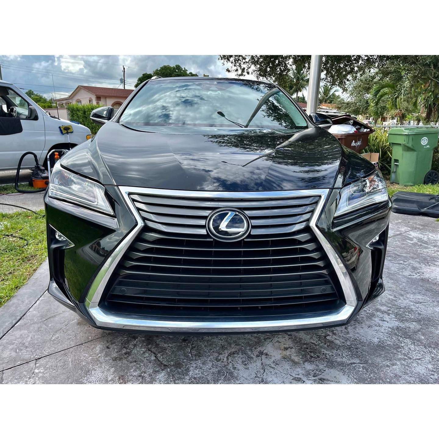 Black Lexus SUV parked in a driveway, front view with chrome grille and headlights visible