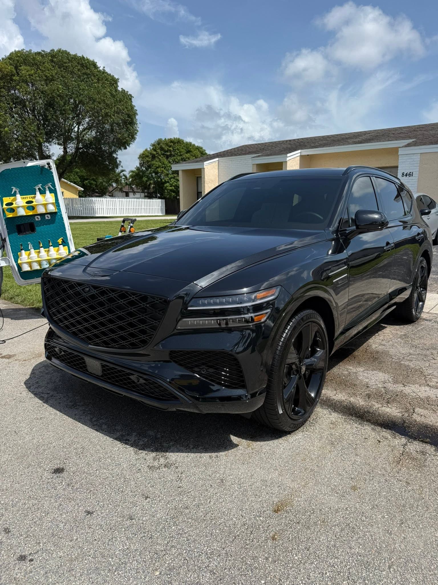 Black SUV parked outdoors on a sunny day beside a building and dumpster