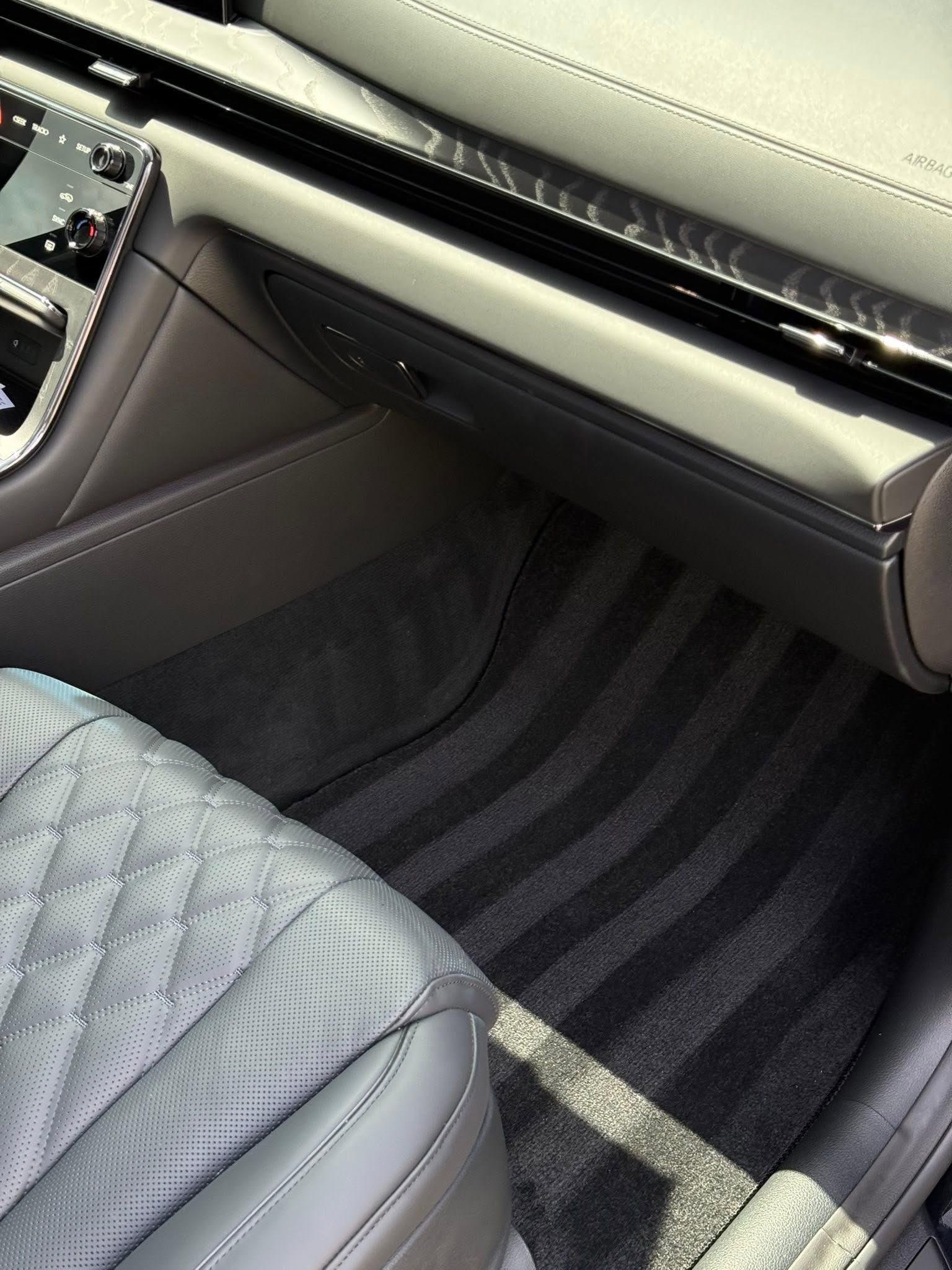 Car interior with gray leather seats and striped floor mats near the dashboard