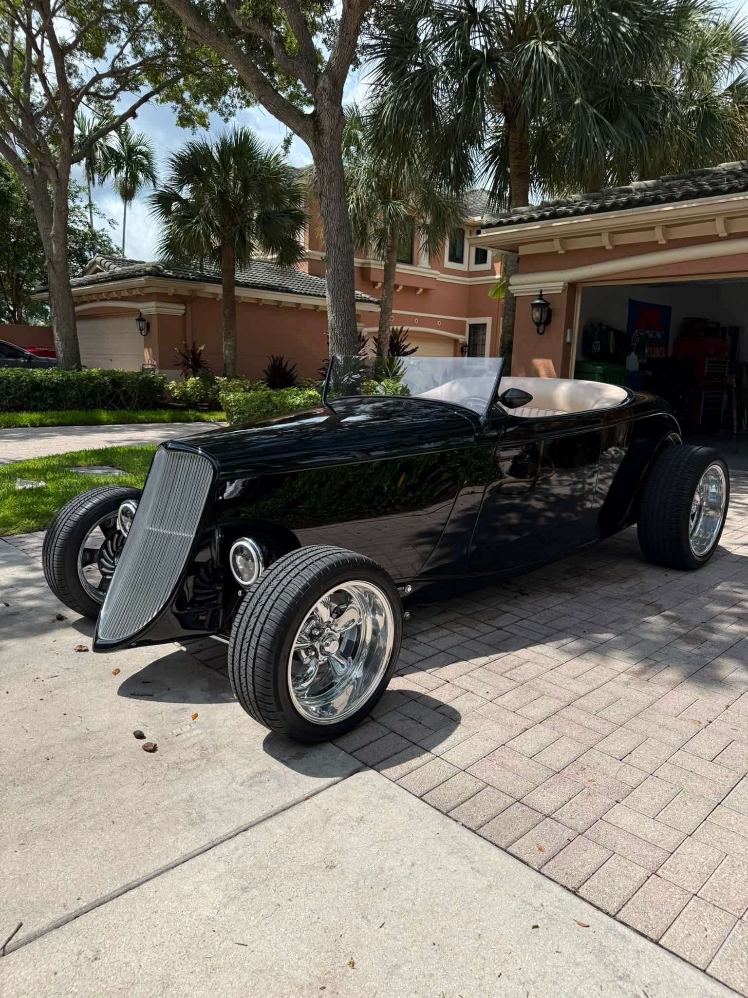 Black vintage hot rod parked in a driveway outside a suburban home