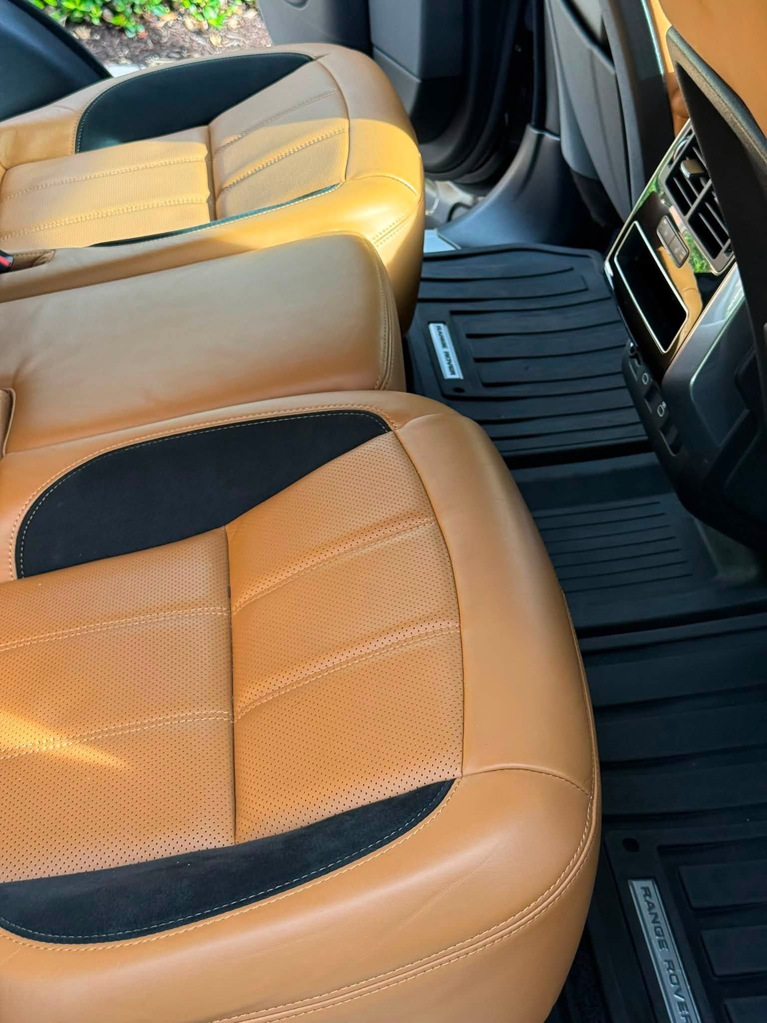 Tan leather car seats with black inserts and floor mats in the back seat area