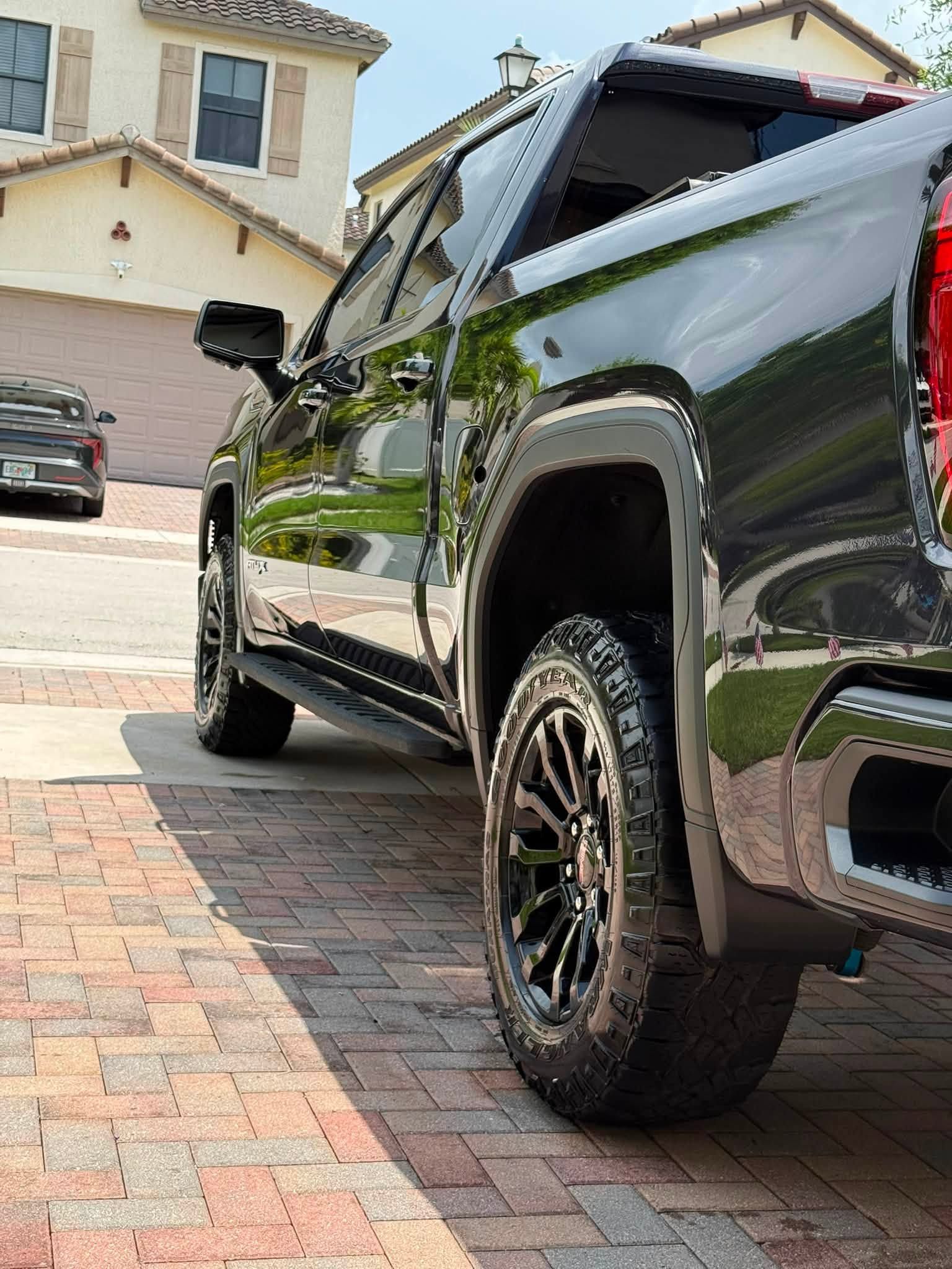 Black pickup truck parked on a brick driveway in front of a house